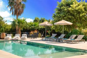a swimming pool with lounge chairs and umbrellas at Cretan Dream Villa in Georgioupolis