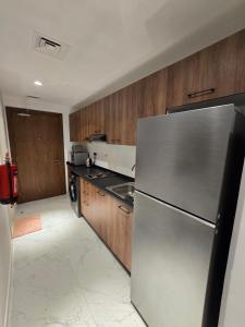 a kitchen with a stainless steel refrigerator and wooden cabinets at شقة مصدر in Abu Dhabi