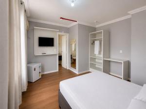 a bedroom with a white bed and a television at iG Hotel - Canasvieiras in Florianópolis +11 photos