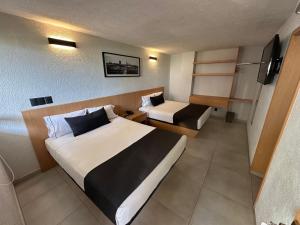 a hotel room with two beds and a tv at Hotel Emperador centro Guadalajara y Remodelado in Guadalajara