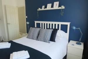 a blue bedroom with a white bed with pillows at Seaside House Broadstairs by the Beach with Parking in Broadstairs