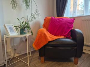 a black chair with a pink pillow next to a table at Seaside House Broadstairs by the Beach with Parking in Broadstairs