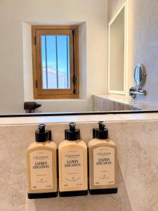 three bottles of soap sitting on a counter in a bathroom at LE PALMIER Aigues-Mortes Petite Camargue in Aigues-Mortes