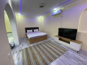 a room with a bed and a flat screen tv at Qoya in Fergana