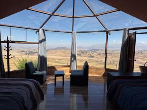 a room with two beds and a large glass window at Sky Dome Peru in Cusco