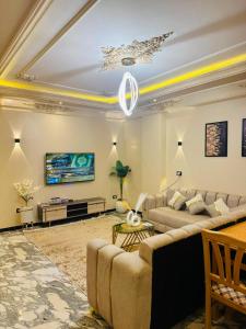 a living room with two couches and a tv at XOtel in Dumyāţ al Jadīdah