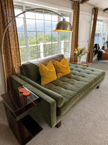 a green couch in a living room with a large window at Mountain Daddies Boutique Bed & Breakfast near Yosemite - Fresh Homemade Breakfast Included in Oakhurst