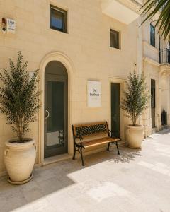 a bench sitting outside of a building with two potted plants at Dar Barbara Suites in Birgu
