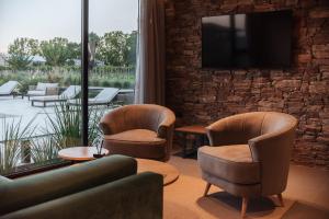 a living room with chairs and a tv on a brick wall at Legado Wine Lodge in Maipú