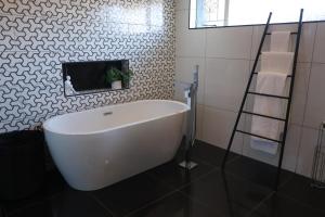 a white bath tub in a bathroom with black tiles at Blue Crane Luxury Accommodation in Welkom