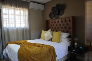 a bedroom with a bed with yellow pillows and a window at Blue Crane Luxury Accommodation in Welkom