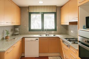 a kitchen with wooden cabinets and a sink and a window at WELCS CASA 423 PDA con piscina in Vall-Llobrega