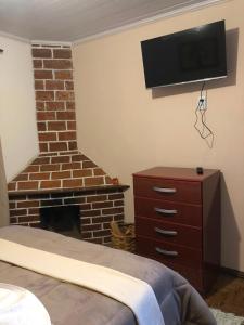 a bedroom with a brick fireplace and a television on the wall at Aconchego Mineiro in Visconde De Maua