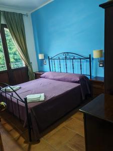 a bedroom with a purple bed with a blue wall at Al Giumani in Mammola