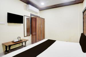 a bedroom with a bed and a wooden table at HOTEL O RAJDHANI in Kānpur +22 photos