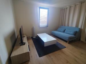 a living room with a blue couch and a tv at Max-El's Home in Geispolsheim