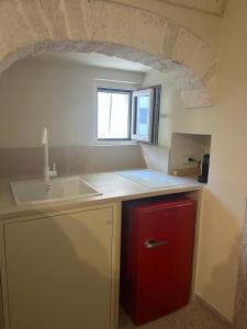 a kitchen with a sink and a red refrigerator at Dimora Noci Mia in Noci