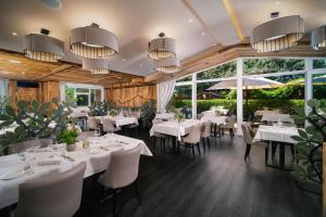 a restaurant with white tables and chairs and large windows at MONDI Hotel Tscherms in Cermes