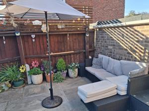 a patio with a couch and an umbrella and plants at Home from home Single or double room Netflix or Virgin TV Wifi & free parking in Poole