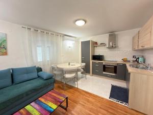 a living room with a blue couch and a kitchen at Apartman Luna in Šibenik