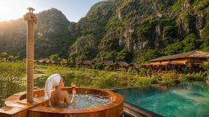 a man in a hot tub with a drink at Karsia Retreat Ninh Binh in Ninh Binh