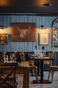 a restaurant with wooden tables and a picture of a bull at le Bistrot des Portes in Les Portes