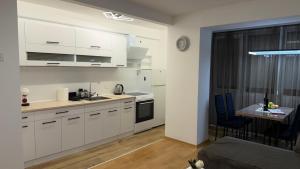 a kitchen with white cabinets and a table in a room at Urban Apartment Karpoš in Skopje