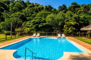 a swimming pool with two lounge chairs and trees at Refúgio das Rosas in Pedro do Rio