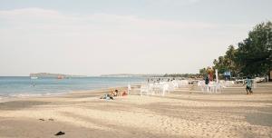 a beach with white chairs and people on the sand at Casa Moon Trincomalee Beach House in Trincomalee