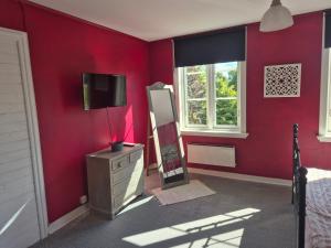 a bedroom with red walls and a tv and a dresser at Vitahästen in Hästveda