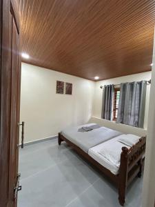 a bedroom with a bed with a wooden ceiling at Spatika Villa in Madikeri