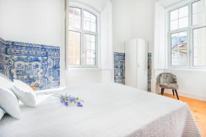 a white bedroom with a large bed with flowers on it at Coeur de Fern in Lisbon