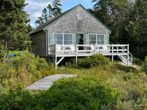 a house with a boardwalk in front of it at Capstone Cottage - Quintessential Cabin on Bay in Gouldsboro