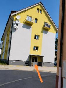 a yellow and white building with an orange arrow at Apartmán Urban Kubín in Dolný Kubín