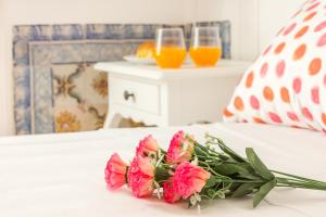 a bouquet of flowers on a bed with two glasses of orange juice at Coeur de Fern in Lisbon
