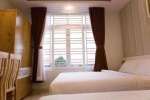 a bedroom with two beds and a large window at Thien Nga Hotel in Buon Ma Thuot +3 photos