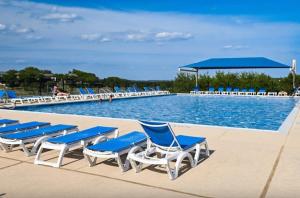 a pool with blue and white lounge chairs next to it at Bright & Spacious Family Home with Firepit, Lake Views, Furnished Deck, Free WiFi in Lago Vista