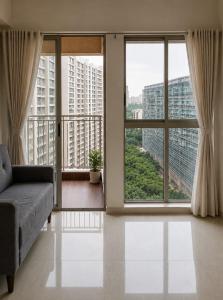 a living room with a couch and large windows at Lodha Crown Premium 2BHK Thane in Thane