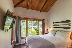 a bedroom with a bed and a large window at Carenero Hills - Beach and Surf Bungalows in Bocas Town