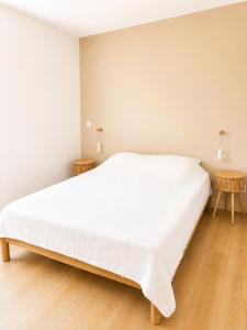 a white bed in a room with two tables at La Cachette du Lac-Douce parenthèse en famille près du lac & piscine in Lacanau +5 photos
