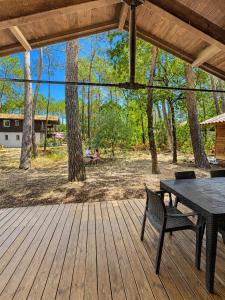 a wooden deck with a table and a bench on it at La Cachette du Lac-Douce parenthèse en famille près du lac & piscine in Lacanau