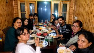a group of people sitting around a table eating food at Forest Glen Cottage in Wāmpor +8 photos
