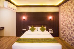 a bedroom with a large white bed with green pillows at Itsy By Treebo - Arastu Inn in Hyderabad