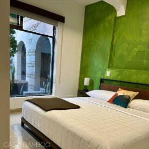 a bedroom with a large bed with a green wall at Casa Bamboo in Mexico City