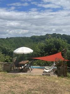a deck with a table and chairs and an umbrella at Logis de Rault in Sainte-Ouenne