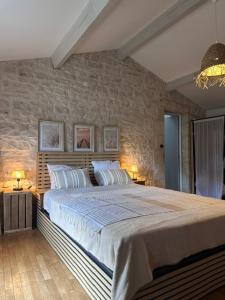 a bedroom with a large bed and a stone wall at Logis de Rault in Sainte-Ouenne