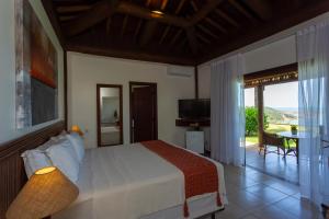 a bedroom with a bed and a balcony with a view at Gungaporanga Hotel in Barra de São Miguel