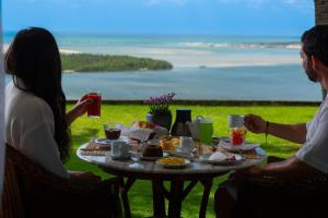 a group of people sitting around a table with food at Gungaporanga Hotel in Barra de São Miguel +20 photos