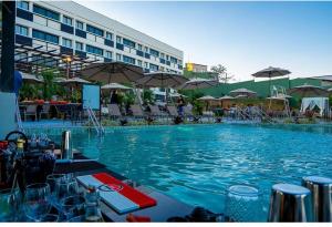 a large blue swimming pool with tables and umbrellas at Hotel Thermas da Mata e Parque aquático - Cotia próximo ao Animália Park in Cotia