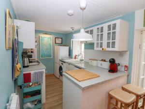 a kitchen with blue walls and white cabinets at Dookers' Hoose in Buckie
